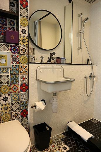 こちらはバスルーム内。なんと、ロビーと同じカラフルでレトロなタイルが敷き詰められています。こんな可愛いらしいタイルのお手洗いがあると、毎日の浴室利用も楽しくなりますね。タイル以外のスペースは、白と黒でスタイリッシュにまとめられていてお洒落。