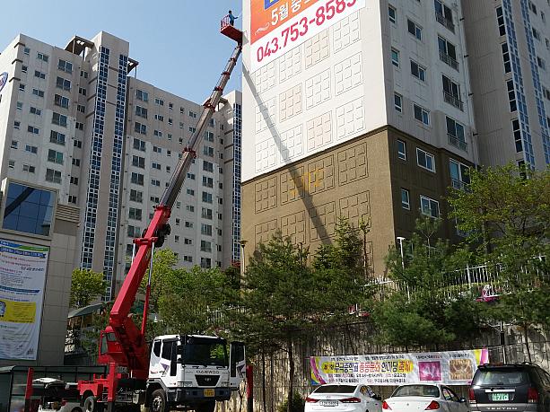 韓国は一軒屋が少なく、高層住宅が多い国。たまたま通りかかった場所でマンションの壁に貼る作業をしていますが