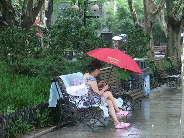 ビニールシートと傘でくつろぐ人。雨の日の公園もけっこう人出があります