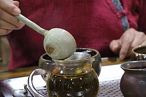 茶湯を大きなスプーンですくって、茶杯に分けます