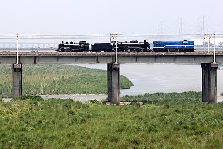日本の国鉄C12形と同型の台鉄保存車CK124（画面左）と同じくD51形と同型のDT668が、ディーゼル機関車Ｒ40にエスコートされ、ゆったりと川を渡り、背中合わせの組成がユーモラス