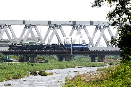 日本の国鉄C12形と同型の台鉄保存車CK124（画面左）と同じくD51形と同型のDT668が、ディーゼル機関車Ｒ40にエスコートされ、ゆったりと川を渡り、背中合わせの組成がユーモラス