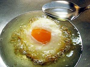 7. フライパンに多めに油を熱したら卵を割り入れ、スプーンで卵の表面に油をかけながら目玉焼きを作る。
☆表面に火が通り、卵の周りがカリカリのきつね色になったら油からひきあげます。黄身まで火を通さず、半熟のままに仕上げるのがコツですよ。
