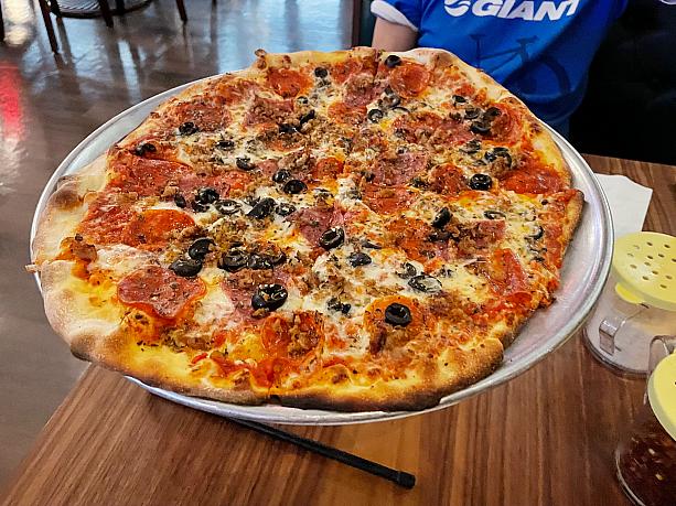 ピザ専門店に全然負けない、おいしーい薄いカリカリピザ。食べた知り合いロコの感想、「ニューヨークスタイルのピザだ」。テーブルに置かれる取り皿はプラスチックのカトラリーを添えた紙皿。ちょっと気抜け‥‥でも気楽。ドリンクはグラスに入ってきますよー。