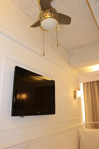 壁備え付けのテレビ。こちらの部屋も、もちろん天井にはファンが。