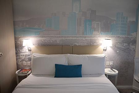 ベットの頭上には淡い色彩で描かれた香港の風景画の壁紙が広いスペースで貼られています。ホワイトの部屋のアクセントになっていて、とってもお洒落ですね。