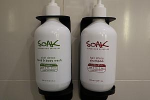 浴室内にセットされたアメニティ。シャワーブース内にあるものはシャンプー＆ボディウォッシュ（左）、シンクの棚には無料の水（中央）、バスアメニティとして歯ブラシ・髭剃り・コットン（右）。