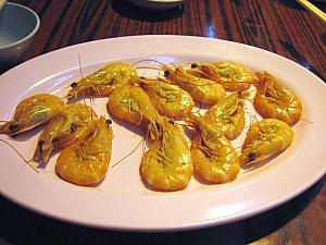 ■ 「白灼蝦（パクチョハー・塩茹で蝦）」<br>
香港式海鮮の定番メニューと言えばこれ。蝦を塩茹でしただけのシンプルな調理法ですが、茹でたての蝦の殻をはずして、唐辛子入りの醤油ダレにつけて食べるその味は、まさに、香港に来てよかった～、と実感するはず。豪快に手でパクリといただくこの料理、誰もが夢中になって食べてしまうおいしさです。おいしさの秘密は、直前まで生きていた新鮮な蝦をさっとゆでることにあります。新鮮なものはシンプルにその素材の味を楽しむものなのですね。これは、前菜的な位置づけですので、最初にオーダーするのがベスト。手を使って食べるため、小さなボウルにお茶を入れた、フィンガーボールをもらって手を洗うことができます。また他に蝦をニンニクでさっと揚げたメニューもあります。