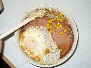 火腿蛋公仔麺と飲み物 <br>
麺は出前一丁のようなインスタント麺で香港では一般的に公仔麺（ゴンチャイミン）と呼びます。トッピングは火腿蛋（ハムと卵）や、朝っぱらからちょっと強烈ですが、五香肉丁（スパイスの効いた豚肉の醤油煮）や沙爹牛肉などが一般的。 