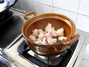 土鍋に生抽と老抽を注ぎ、炒めた豚バラ肉、水を入れ、よく肉とからめておく