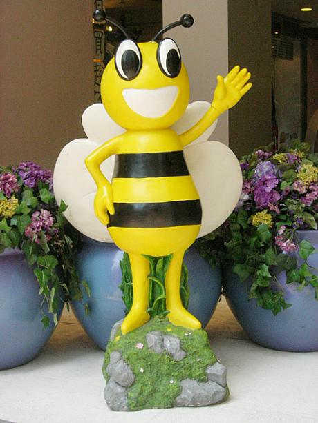 ショッピングモールの入り口でお花に囲まれて、手を振るのはミツバチ。