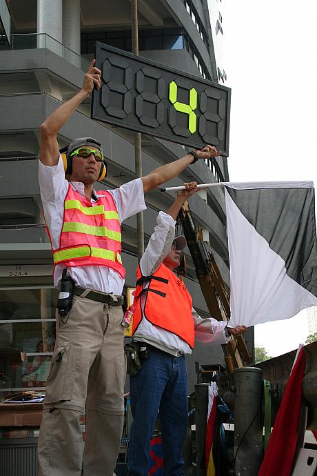 コースマーシャルは各種の旗を振って周辺の状況を伝えます。これはカーナンバー4番がスポーツマンシップらしくない運転をしていることを警告しています