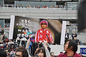 ティータン騎手のポスターを掲げるファン