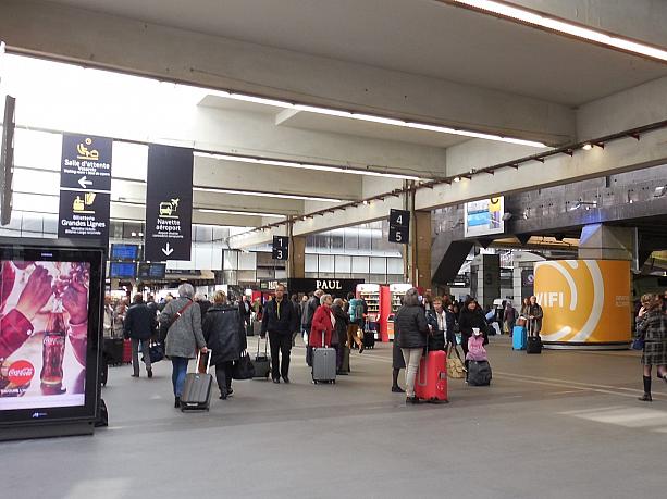 ここはモンパルナス駅。フランスの地方やパリ郊外に行く電車が多数乗り入れるターミナル駅の一つです。スーツケースを持った人たちの姿が目立ちます。
