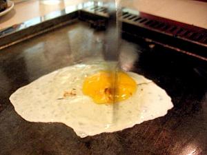 鉄板の上で卵が割られてササッと混ぜるように潰したあと→