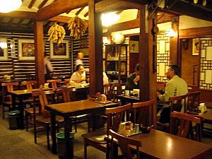 昔の韓国家屋。入口を入ると右手にトンチミ（大根水キムチ）のツボが漬けた日ごとに並べられている。これはなかなか見られない珍しい光景。全体的に木造の趣ある店内。 客席はテーブルと座敷の両方あり。
