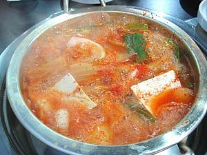 お鍋にフタをしたまま登場。開けてみるとまだ生？今から調理するという感じ。スープは赤いけれど、透明感があり、ちょっと薄そうな感じ。 