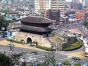 東大門は宝物（ポムル・日本で言う国宝と重要文化財の間）第１号に指定され、本来の名は「興仁之門（フンインジムン）」。ソウル城郭の東側の門です。現在の門楼は1869年に再建されたもの。この東大門の最大の特徴は、門の外を「甕城」が取り巻いているという点。低地なので外敵の攻撃を受けやすいため、このような城壁で防御していました。石を積んだ中央には虹霓門を据え、その上に正面５つ、側面２つの重層門楼を建て、屋根は隅進角（ウジンガク）。軒上には厄除けの意味で動物の像があります。東大門は細部の技法が脆弱で装飾重視になっており、李朝後期の典型的な様式をよく表しています。

