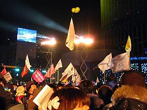 デモ隊たちと旗。ロウソクを紙の灯篭に入れたものを飛ばしていたけれど（写真右）・・・落ちたら危ないなあ・・・ 
