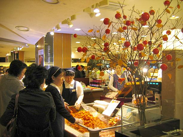 一方こちらは高級百貨店のデパ地下。キレイな柿の木の飾りの下で大量の干し柿が売られています。