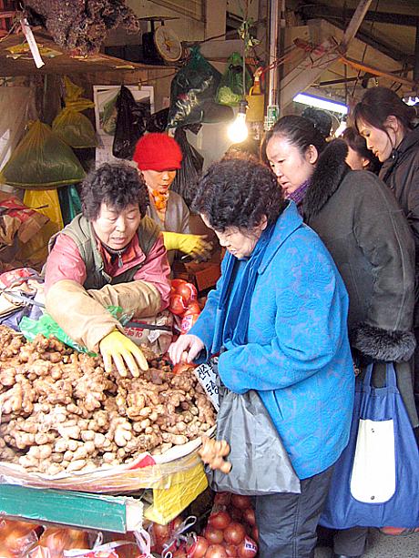 野菜、果物、肉、魚、調味料などあらゆる食材が揃うこの市場は、ソルラルなどの名節前になるとこんなふうに買い物客がたくさん押し寄せます。生姜一つにもこんなに人が集まる！市場の人たちも、ここがかき入れ時っ！と商売に熱が入る！