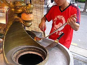 ヨン（竜）がパンをくわえています。深い鍋のようになった焼き釜の中には、側面にへばりついたパンが。「一つ2,000ウォンだよ～」（byお兄さん）