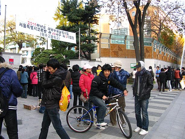 今日は、全国一斉に行われる大学入試試験、「大学修学能力試験」略して「スヌン(修能)」の日！試験会場となっている高校の前には、朝早くからたくさんの人がつめかけています！