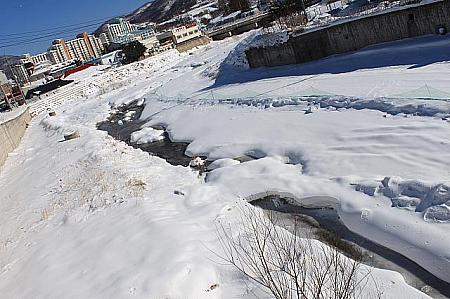 中学校付近の門には大関嶺雪花まつりの横断幕が。橋の下を流れる川は凍り、雪に覆われていました！