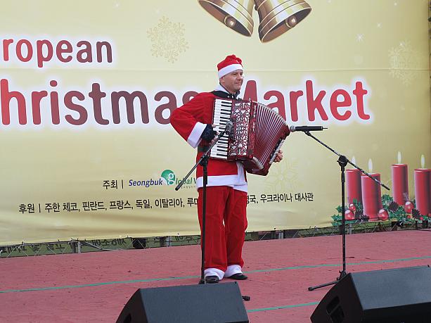 ステージの上ではサンタがアコーディオンでクリスマスソングを演奏中～♪　このマーケット、明日の土曜日まで行われています。
