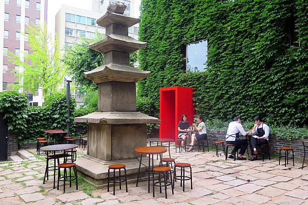 古い塔と、現代的なテーブルや建物の赤い入口とが対照的で独特の雰囲気～