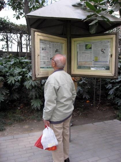 公園内に設置されている新聞コーナーで、新聞を読むおじいちゃん。