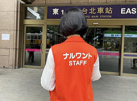 ナルワントツアーのオレンジ色のジャケットを着たガイドが<b>台北駅「東一門」入口の内側</b>でお待ちしております！