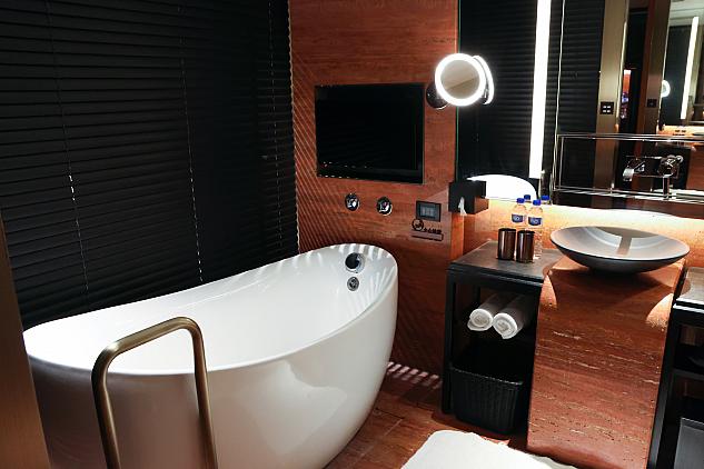 バスルーム。バスタブ前のTVにも注目!ベッドルームとの間の壁はガラス。プライベートを保ちたい場合はブラインドを閉めて入浴を