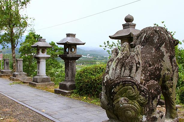 狛犬が高台から緑の美しい竹山の風景を見下ろしています。