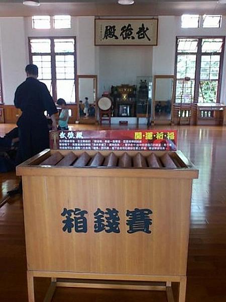 殿内には賽銭箱、その後ろには剣道の練習をしている子供が。