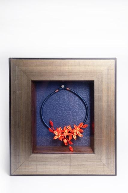 これは『祝福』。巻き花が額縁に入れられている作品です。革のペンダントに巻き花を合わせています。また違った角度から巻き花を楽しめます。