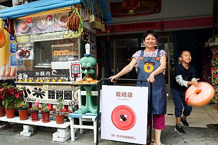 学生の作品である「小米甜甜圏」の看板とおかみと次期(？)店主。本業はお直し屋さんだから表裏異なるデザインに