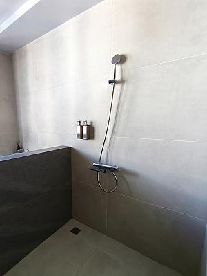 バスタブ＋シャワーブース＋トイレは部屋の一番奥、窓側にあります。広々とした開放的なデザイン！ブラインドを下ろせば外からの視線も遮ることができます。けれど、トイレとシャワー＆お風呂は同時に使用するには視線が気になる……。あと、シャワーの水がトイレ側にはねちゃうのもちょっぴり気遣う点です。