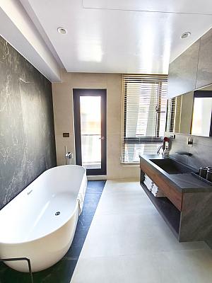 バスタブ＋シャワーブース＋トイレは部屋の一番奥、窓側にあります。広々とした開放的なデザイン！ブラインドを下ろせば外からの視線も遮ることができます。けれど、トイレとシャワー＆お風呂は同時に使用するには視線が気になる……。あと、シャワーの水がトイレ側にはねちゃうのもちょっぴり気遣う点です。