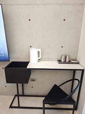 シンプルなデスクに電気ポットが置かれています。水はウォーターサーバーから自分で入れるエコスタイルです。