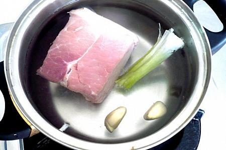 ２．鍋に湯を沸かし、つぶした生姜（またはニンニク）、葱の白い部分、塩少々と豚肉を入れてゆでます。火が通ればとり出して氷水につけて冷まし、薄切りにします。